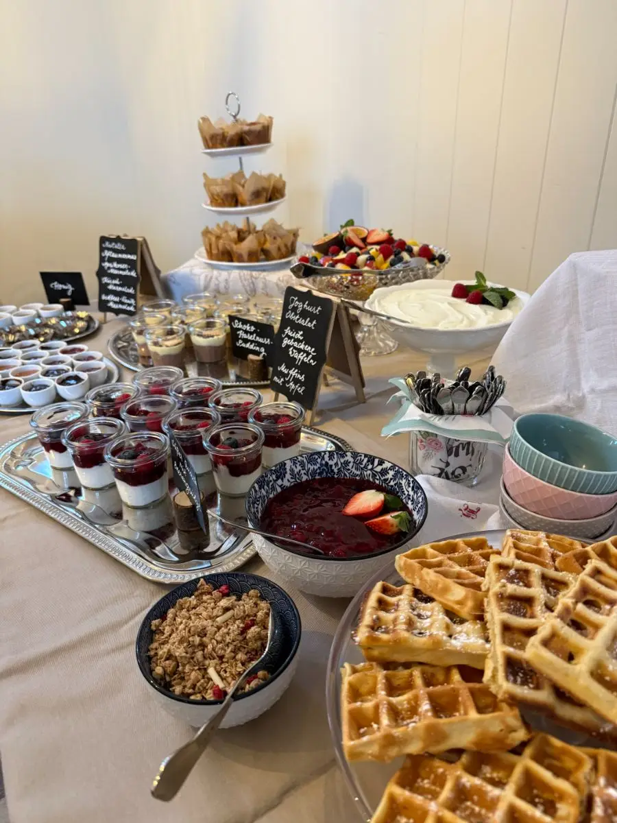 Frühstücksbüfett mit frisch gebackenen Waffeln, Muffins, Obstsalat und Joghurt